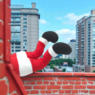 Red and white plush toy with black shoes on a brick ledge against a cityscape background