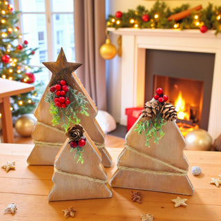 Wooden Christmas tree decorations with pinecones and berries on a table in a festive room with a fireplace and Christmas tree.