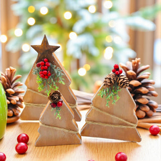 Wooden Christmas tree decorations with pine cones and berries on a wooden surface.