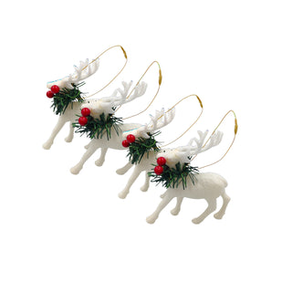 Set of white reindeer ornaments with red berries and greenery on a light wooden surface