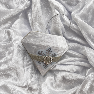 White velvet diamond bauble with silver band and rhinestone buckle on crushed white velvet