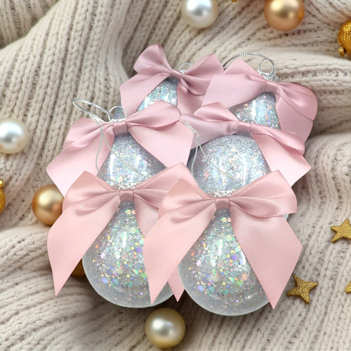 Decorative Christmas ornaments with pink bows on a textured surface.