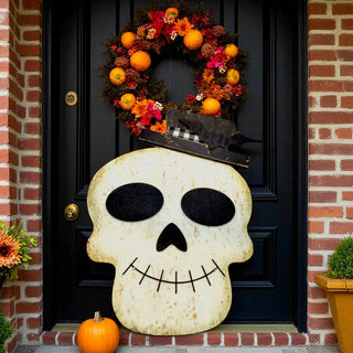 Decorative skull and wreath on a black door with brick columns