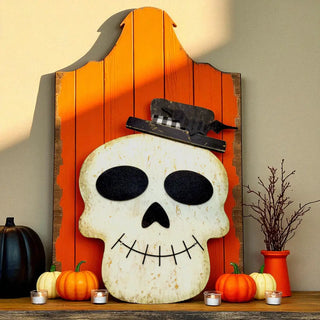 Decorative skull with a witch hat on an orange wooden board with pumpkins and candles.
