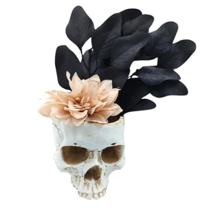 Decorative skull with a peach flower and black leaves on a white background