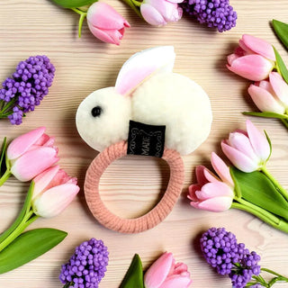 Floral wreath with a plush toy bunny in the center on a wooden surface