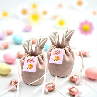 Two bunny-shaped Easter bags with tags on a white background with colorful Easter eggs.