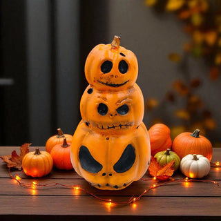 Stack of Halloween-themed pumpkins with carved faces on a wooden surface with string lights and leaves.