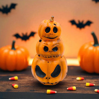 Stack of Halloween-themed pumpkins with a smiling face on a wooden surface with candy corn and pumpkins in the background.