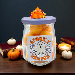 Glass jar filled with Halloween-themed items on a dark background