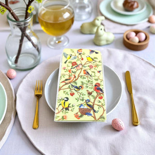 Decorative table setting with a colorful bird-themed napkin on a white tablecloth.