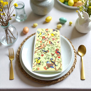 Easter table setting with a decorative napkin featuring birds and flowers on a white plate.