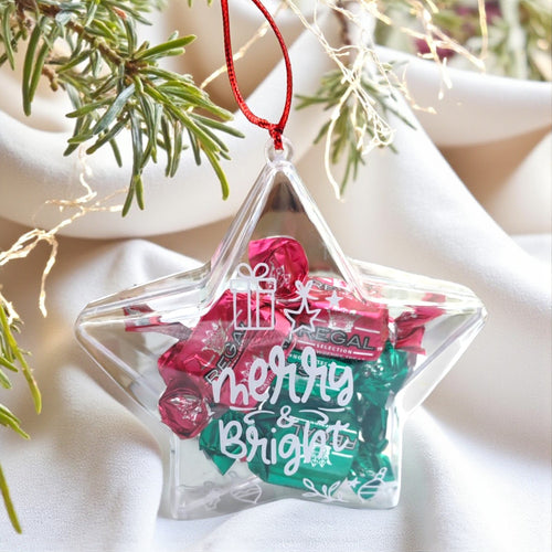 Star-shaped clear ornament with candy and 'Merry & Bright' text, hanging on a Christmas tree.