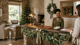Woman sitting at a desk in a cozy room with a Christmas tree and wreath.