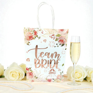 Floral 'Team Bride' gift bag with champagne and roses on a white background
