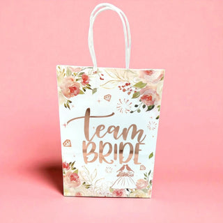 Gift bag with 'Team Bride' text and floral design on a pink background