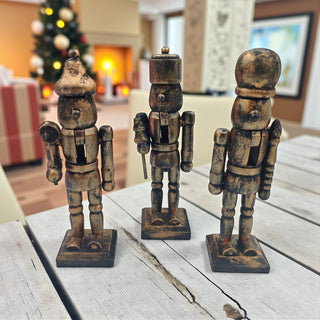 Three wooden nutcracker figurines on a table with a festive background.