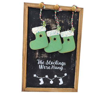 Decorative sign with green stockings and text on a black background
