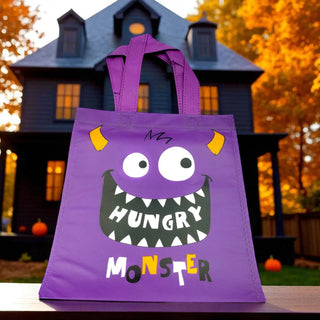 Purple Halloween bag with monster design in front of a haunted house.