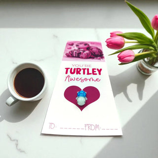 Card with 'You're Turtley Awesome' text, coffee cup, and flowers on a marble surface