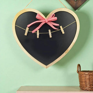 Heart-shaped blackboard with a pink bow and clothespins on a light green background