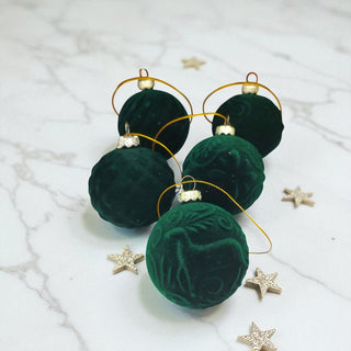 Green velvet ornaments with gold wire on a marble surface