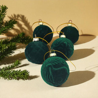 Green velvet ornaments with gold ribbons on a beige background