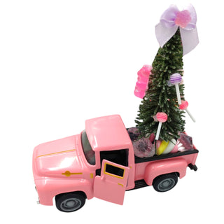 Pink toy truck with a Christmas tree and candy on a white background