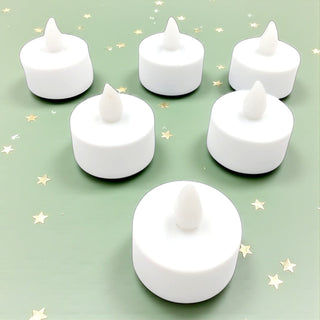 Set of six white LED candles on a light green background with star patterns