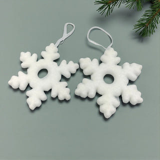 Two white snowflake ornaments on a gray background with greenery.