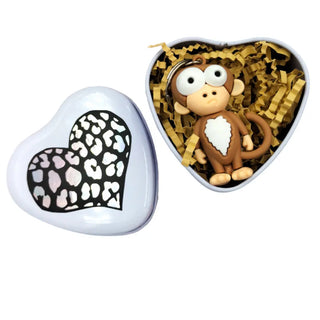 Heart-shaped container with a monkey keychain and leopard print heart on a white background