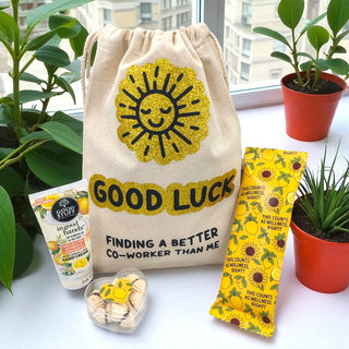 Good Luck drawstring bag with sun design, surrounded by plants and small items on a light surface.