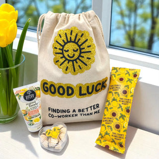 Good Luck drawstring bag with sun design, sunflower-themed products, and a vase of yellow tulips on a windowsill.