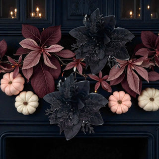 Decorative arrangement of pumpkins and dark flowers on a dark background