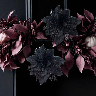 Decorative wreath with dark purple and black flowers on a black background
