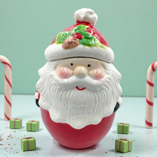 Vintage-inspired Santa treat jar displayed on a neutral kitchen shelf with greenery and fairy lights, warm holiday vibes.