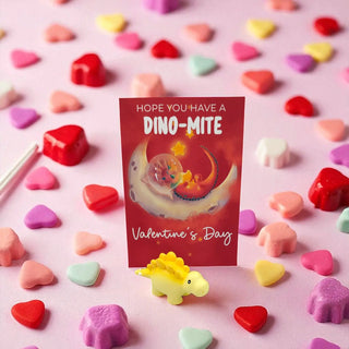 Valentine's Day card with dinosaur illustration surrounded by colorful candy hearts on a pink background