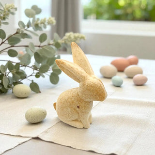 Wooden rabbit figurine with Easter eggs on a tablecloth