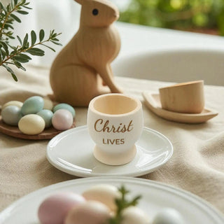 Easter-themed table setting with egg cup, pastel eggs, and wooden rabbit.