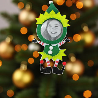 Elf-shaped photo frame ornament with a blurred Christmas tree background