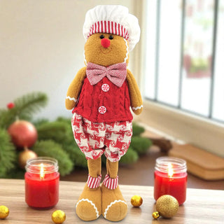 Gingerbread man toy in a red outfit with candles and Christmas decorations on a table.