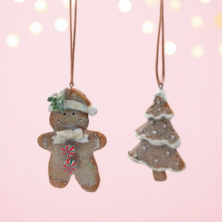 Two Christmas ornaments, a gingerbread man and a tree, on a pink background with lights.