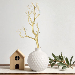 White textured vase with gold branches on a light surface