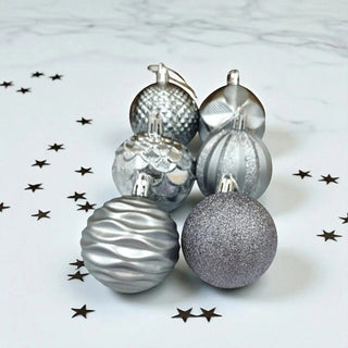 Silver Christmas ornaments on a marble surface with star decorations.