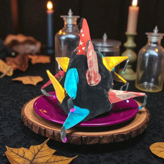 Colorful dragon figurine on a wooden base with candles and leaves in the background