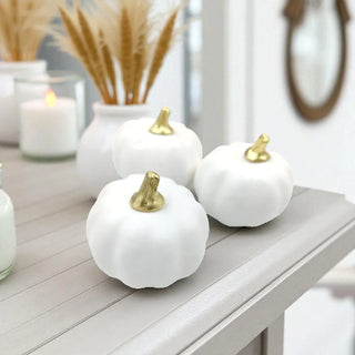 White pumpkins with gold stems on a wooden surface