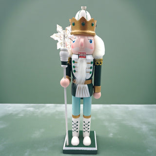 Decorative nutcracker figure with a crown and staff on a white background for a sage Christmas aesthetic
