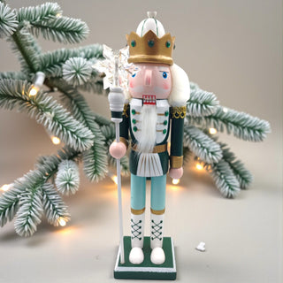 Decorative nutcracker figure with a crown and staff on a white background for a sage Christmas aesthetic