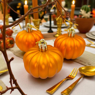 Decorative pumpkins on a table with gold utensils and candles