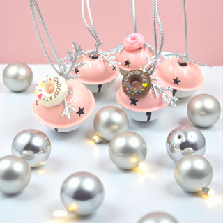 Decorative necklaces with donut and cupcake pendants on a pink background